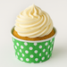 Freshly baked cupcake topped with vanilla frosting, displayed in a green polka dot baking cup, perfect for party or bakery presentation.
